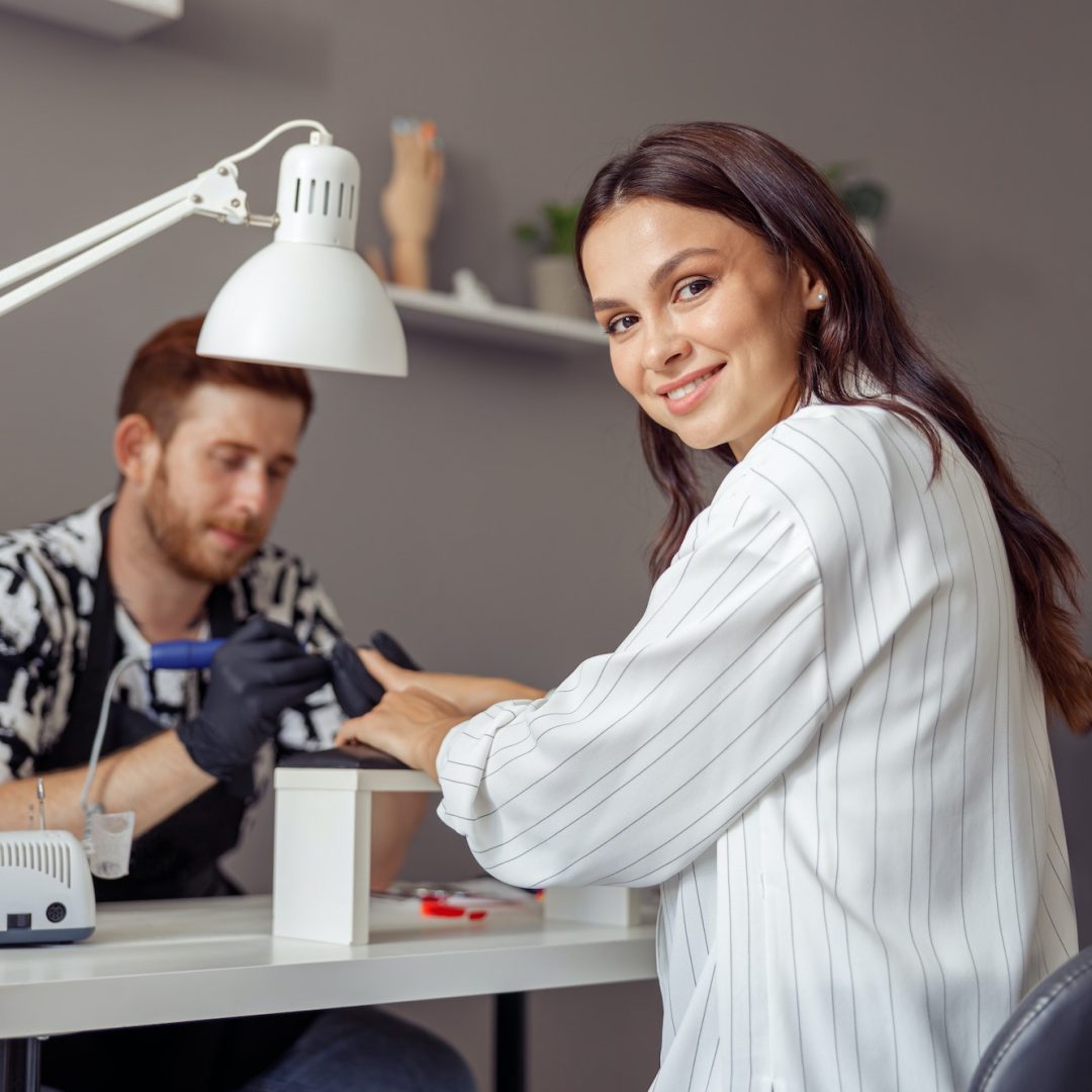 Manicure specialist providing nail service for client in salon